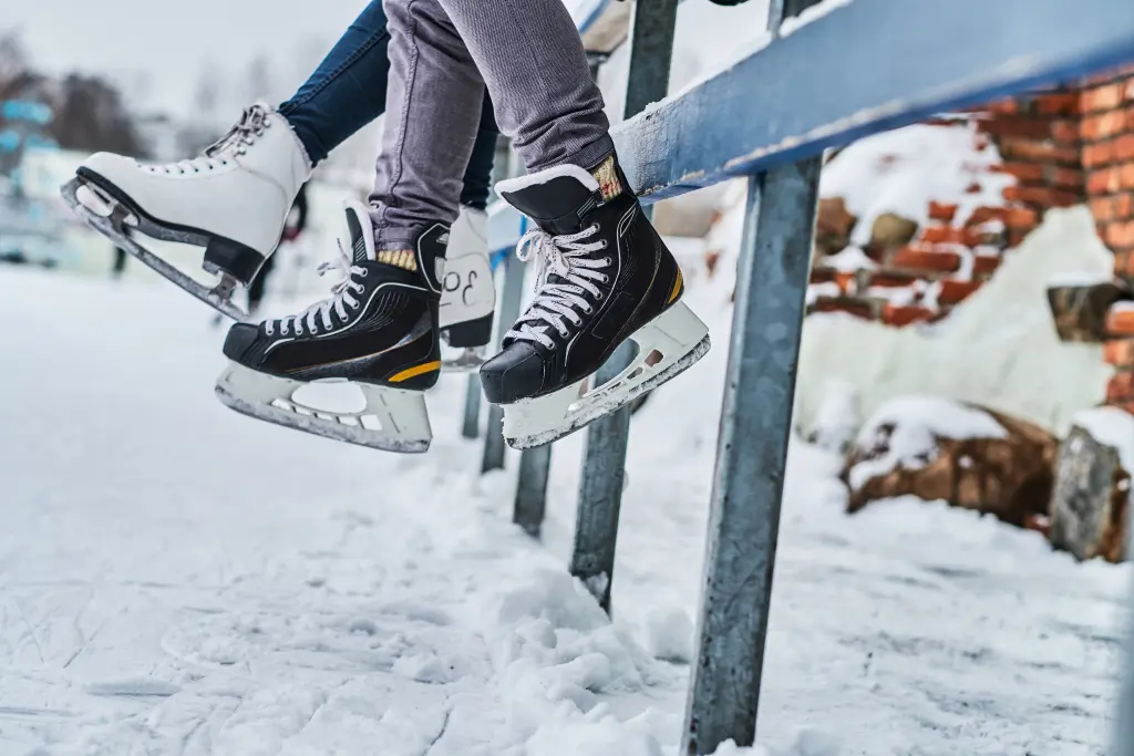 couple-wearing-ice-skates-sitting-guardrail-dating-ice-rink-close-up-view-skates.jpg